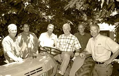 Gotelli posing with a group of farmers around a tractor